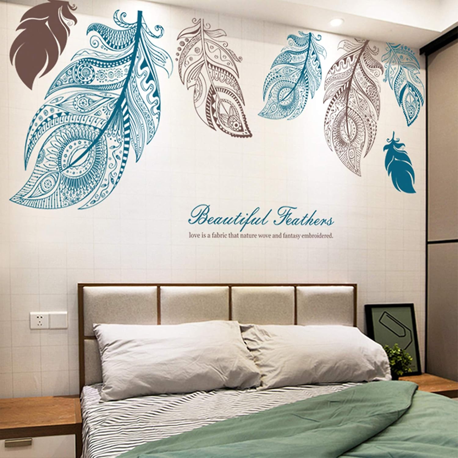 Bedroom with decorative wall stickers of feathers and a quote on a white wall.