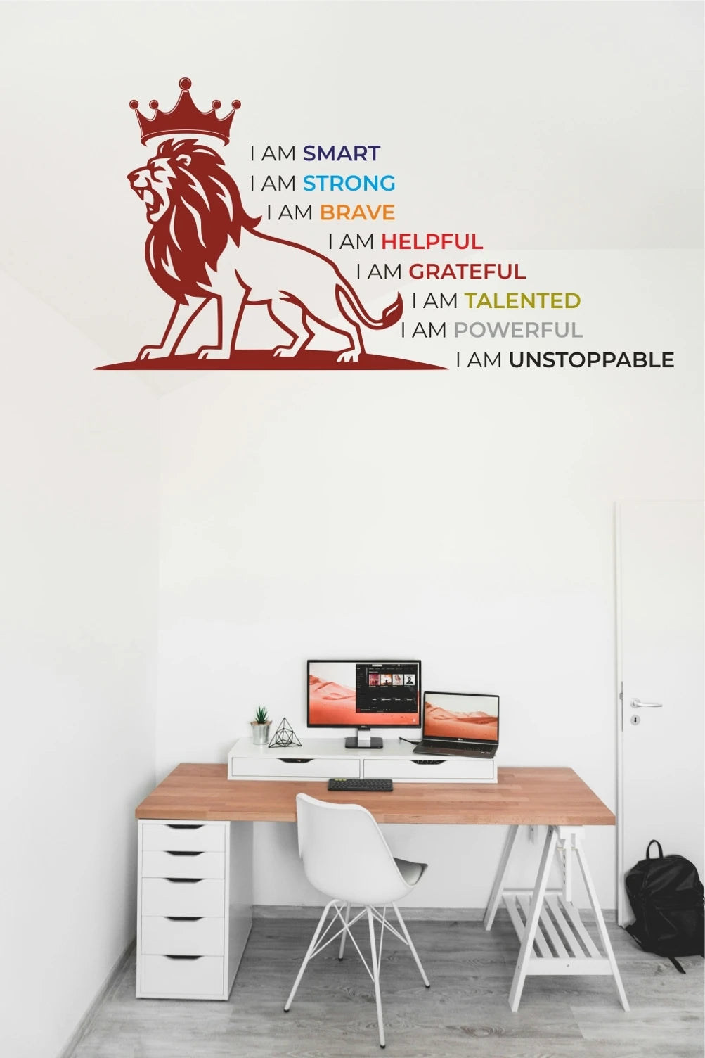 Wall decal of a lion with motivational phrases above a desk setup.