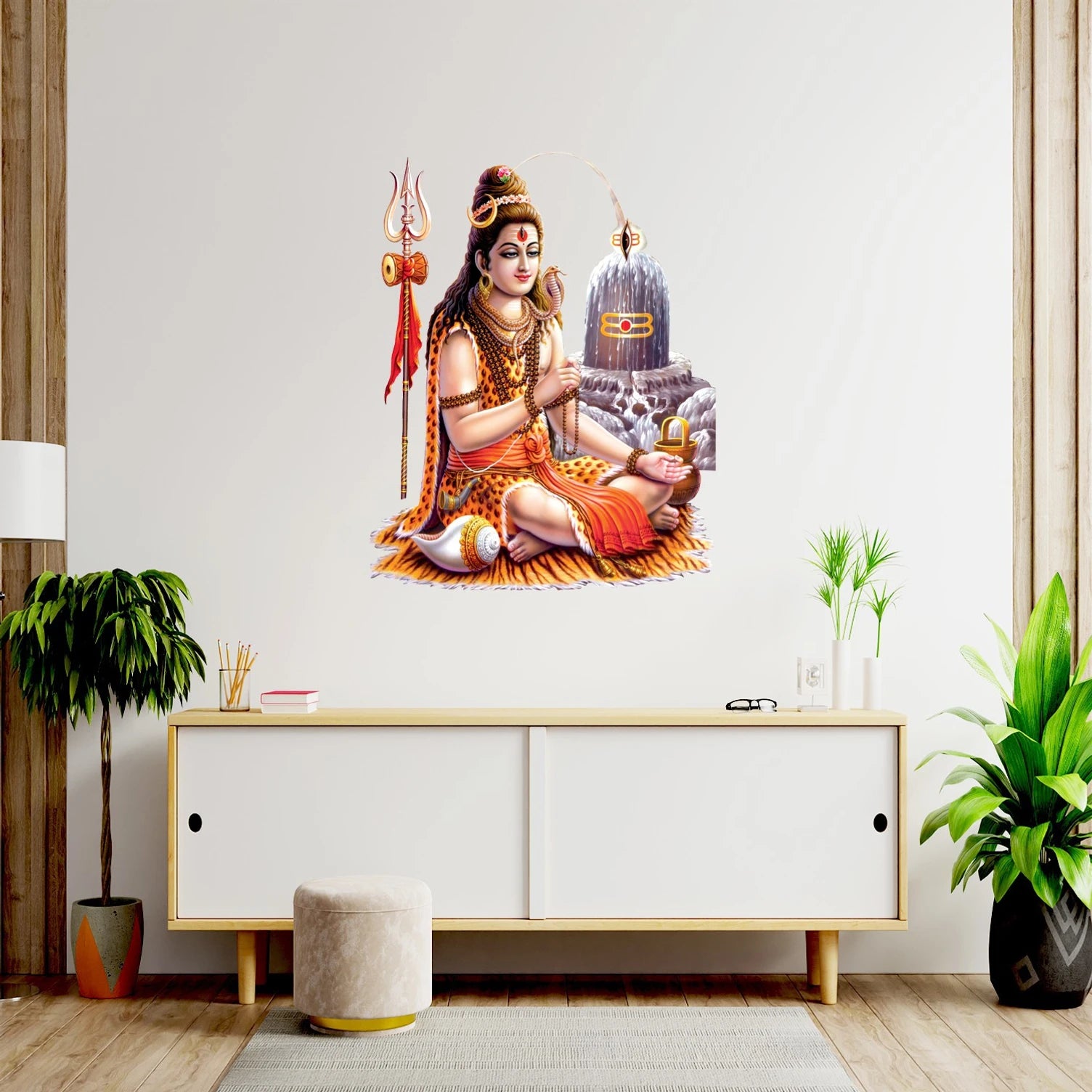 Wall decal of a Shiva on a wall above a white cabinet with plants around.